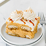 Single slice of pumpkin spice latte tiramisu on a white plate drizzled with caramel sauce