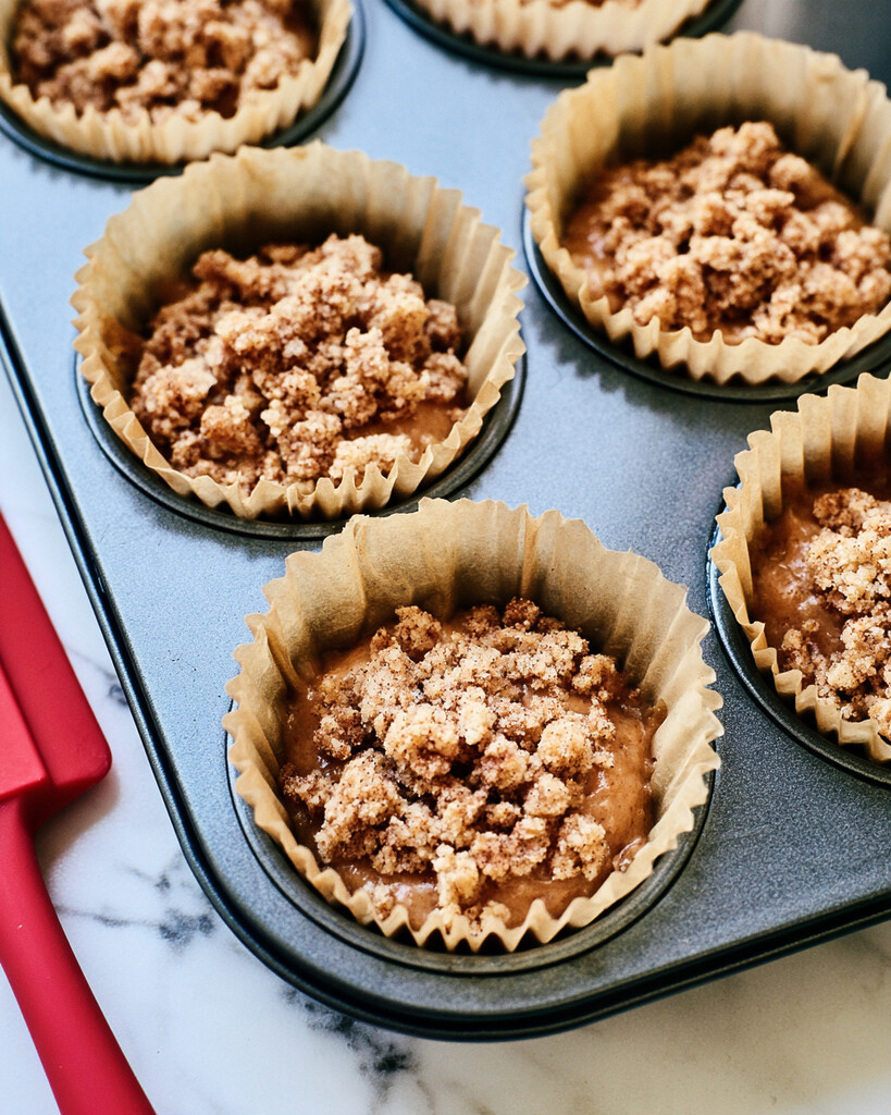 Muffin tin filled nearly to the top with batter and covered generously in brown butter streusel before baking