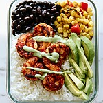 30-Minute Meal Prep Blackened Shrimp Bowls Blackened shrimp bowl ready to serve with rice, black beans, corn, and a drizzle of avocado crema
