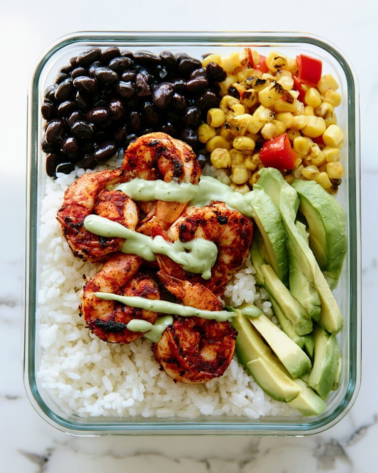 30-Minute Meal Prep Blackened Shrimp Bowls Blackened shrimp bowl ready to serve with rice, black beans, corn, and a drizzle of avocado crema