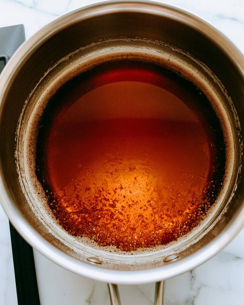 Melted butter bubbling and foaming in a metal saucepan with an amber tint