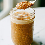 Make-Ahead Pumpkin Spice Latte Overnight Oats A spoon lifting a thick bite of spiced overnight oats and creamy white foam from a glass jar