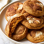 Pumpkin snickerdoodle broken in half on a plate showing a soft orange center