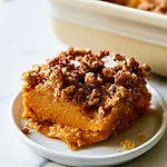 Salted Pecan Pumpkin Dump Cake with a Cobbler Crunch Square slice of salted pecan pumpkin dump cake showing smooth orange filling and crunchy topping on a white plate