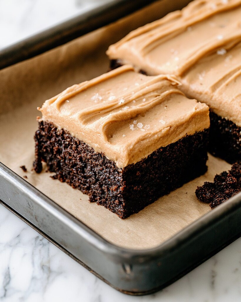 Mounds of frosted chocolate espresso cake cut into squares inside the baking pan