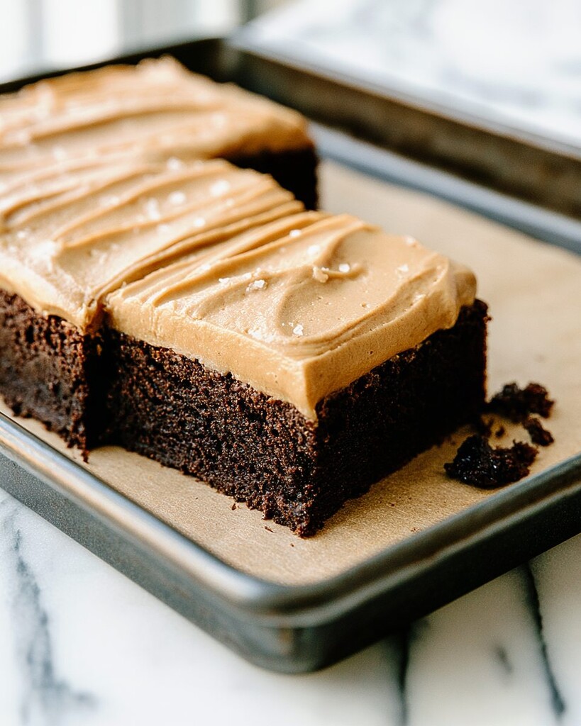 Close up of frosted chocolate cake slices resting next to dark chocolate crumbs