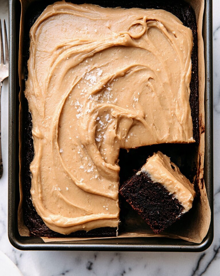 Dark Chocolate Espresso Sheet Cake with Brown Butter Frosting Overhead view of a dark chocolate espresso sheet cake with swirled brown butter frosting and a missing slice