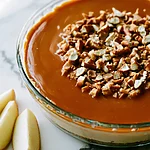 No-Bake Caramel Apple Dip with Toffee and Pretzels Caramel apple dip with toffee and pretzels in a glass dish showing a glossy caramel top and apple wedges