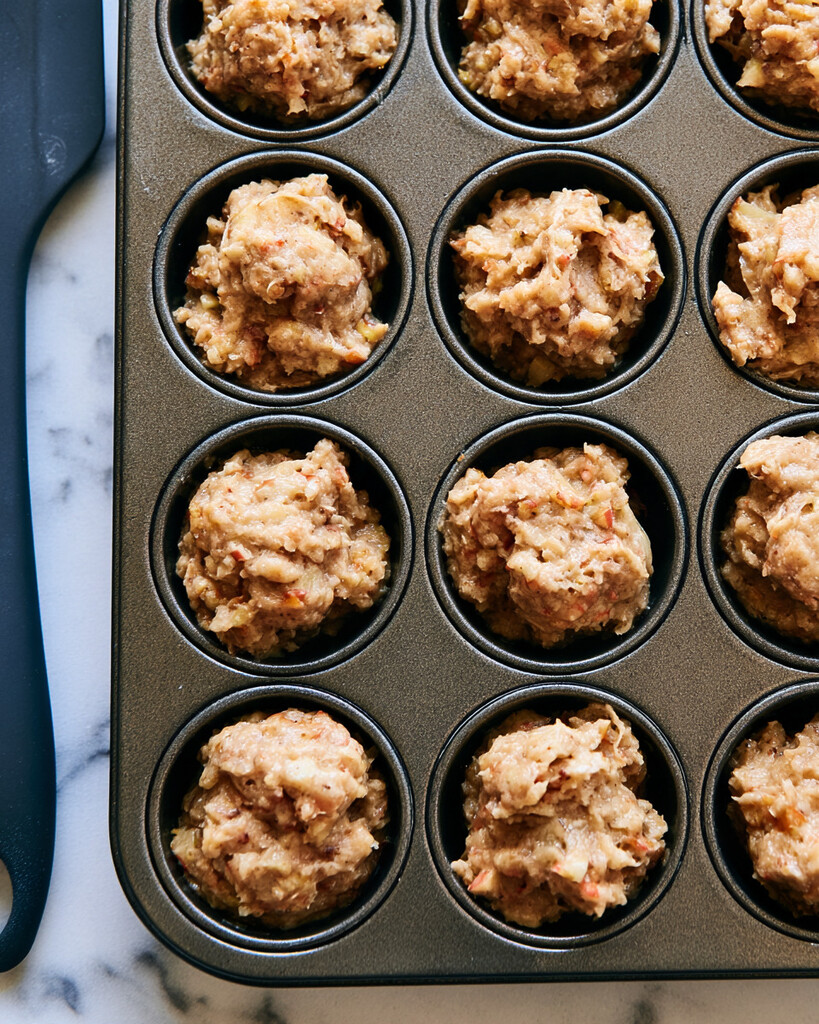 Thick shaggy apple fritter dough with visible apple pieces portioned into a mini muffin pan