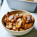 Maple-glazed apple pan dowdy in a ceramic bowl with sliced apples, browned pastry pieces, and glossy maple sauce