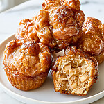 Baked Apple Fritters with Maple-Cider Glaze and Broiled Tops Baked apple fritters with maple-cider glaze on a white plate showing a glossy caramelized crust and apple-filled crumb