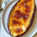 Close-up of torched Japanese sweet potato crème brûlée with a glossy amber caramel crust and flaky sea salt